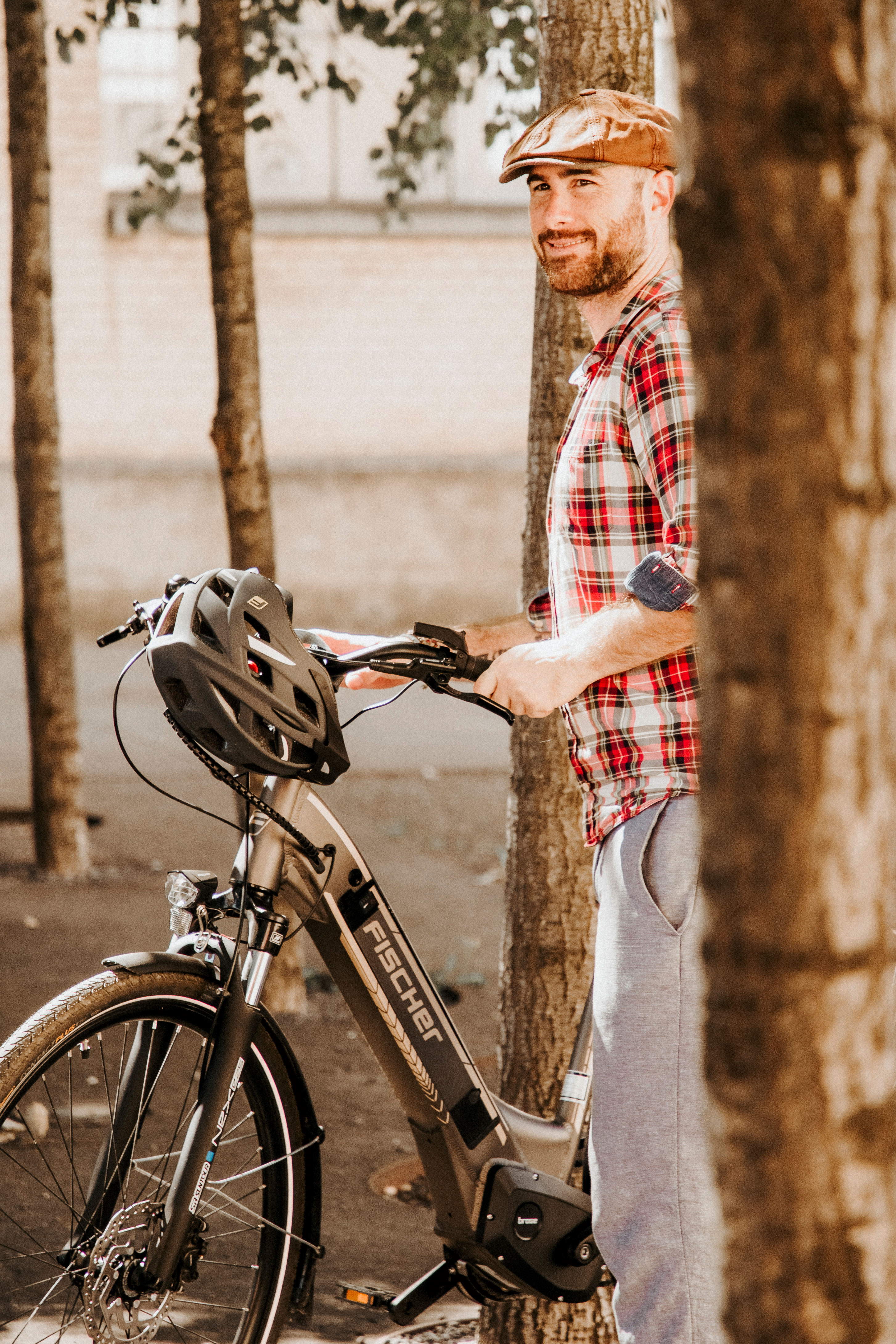 Ein Mann mit einem Fahrradhelm lächelt und schiebt sein E-Bike.